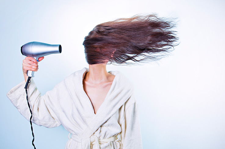 Strom im Badezimmer - eine Frau föhnt sich die Haare